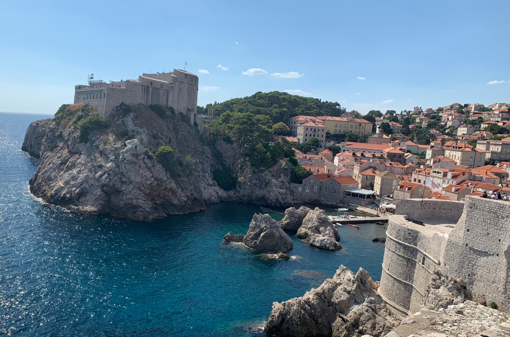 Blick auf die historische Festung Lovrijenac auf einem Felsen über der Adria und die Altstadt von Dubrovnik bei sonnigem Wetter.