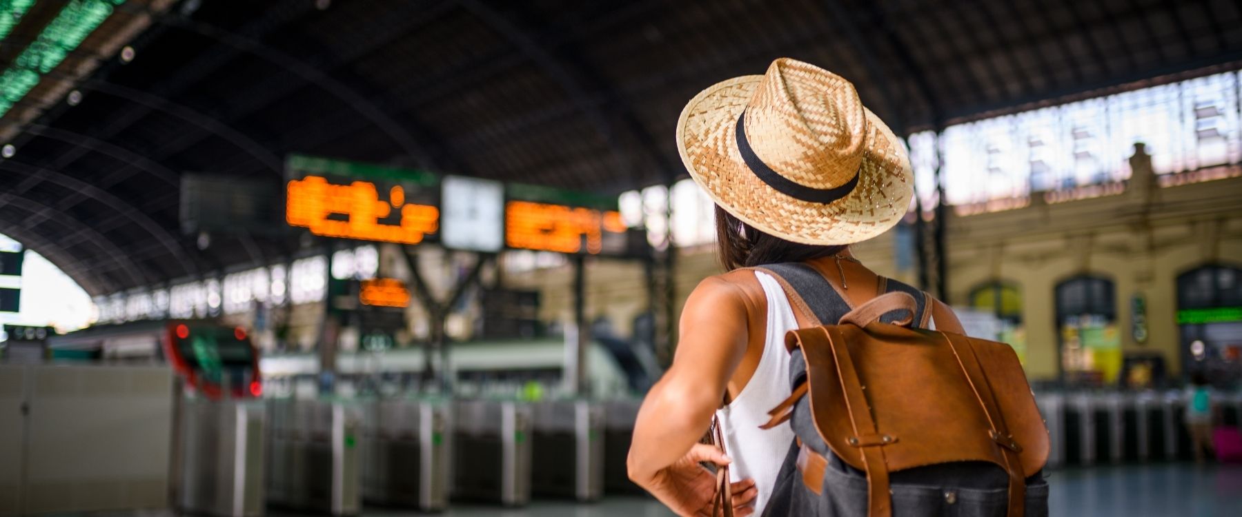 Reisende mit Rucksack auf einem Bahnhof.
